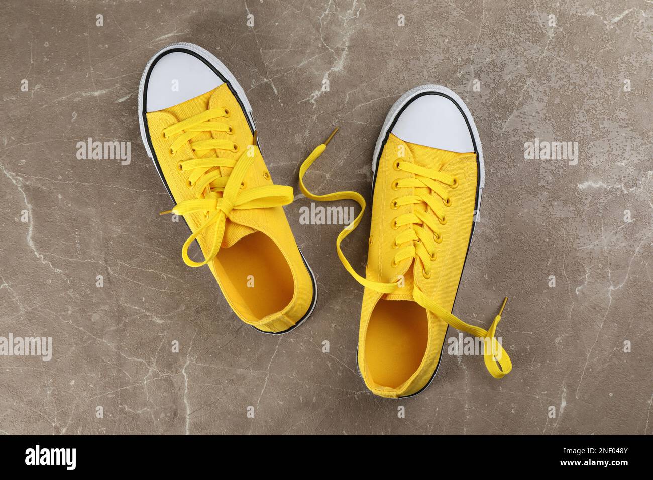 Paio di sneaker gialle su tavolo in pietra grigia, a posa piatta Foto Stock