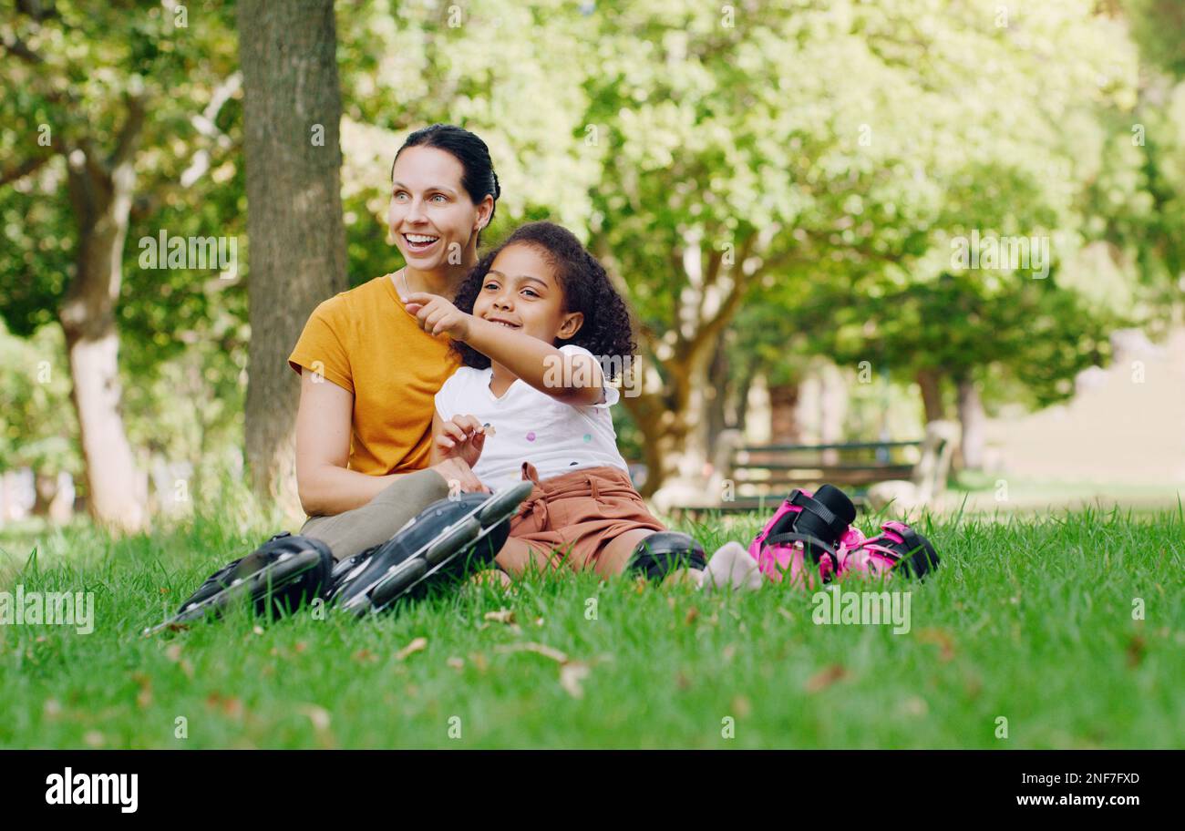 Famiglia, madre e bambino nel parco con rollerblade all'aperto, rilassarsi sull'erba e divertimento nella natura con persone felici. Donna, ragazza e fare una pausa Foto Stock