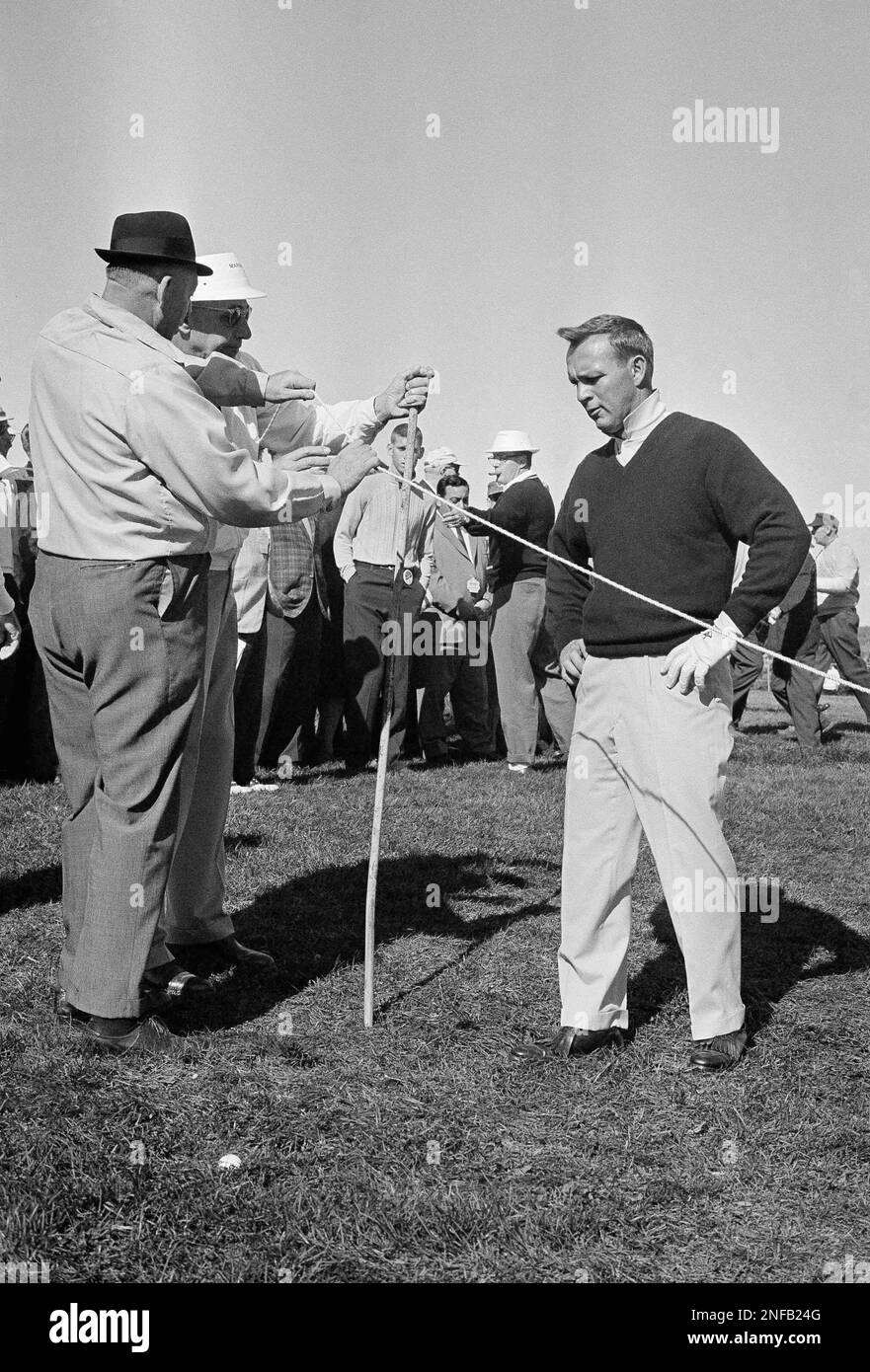 Arnold Palmer, king of the pro golf money winners, holds hands on hips and frowns as he studies ball in rough and groundskeepers lower rope for him to play in Whitemarsh Golf Club near Philadelphia, Oct. 4, 1963. Palmer's ball went off fairway on 12th hole in second play of the 72-hole tourney. (AP Photo/Bill Ingraham) Foto Stock