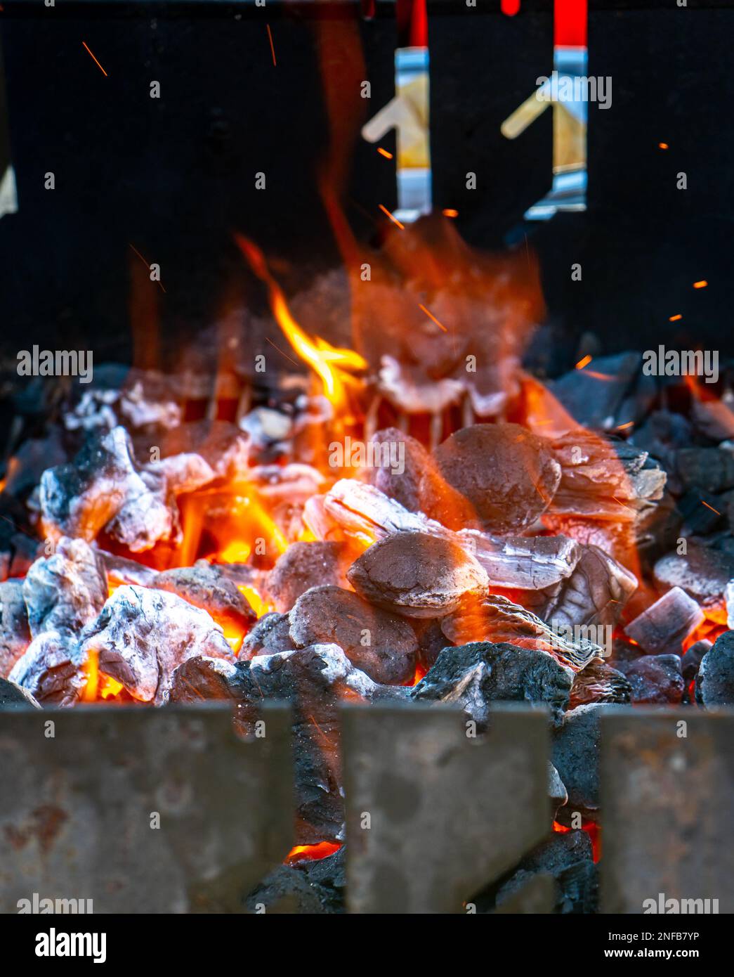 Carbone e brace che brucia a piena capacità al suo picco in un barbecue di metallo e fumo Foto Stock
