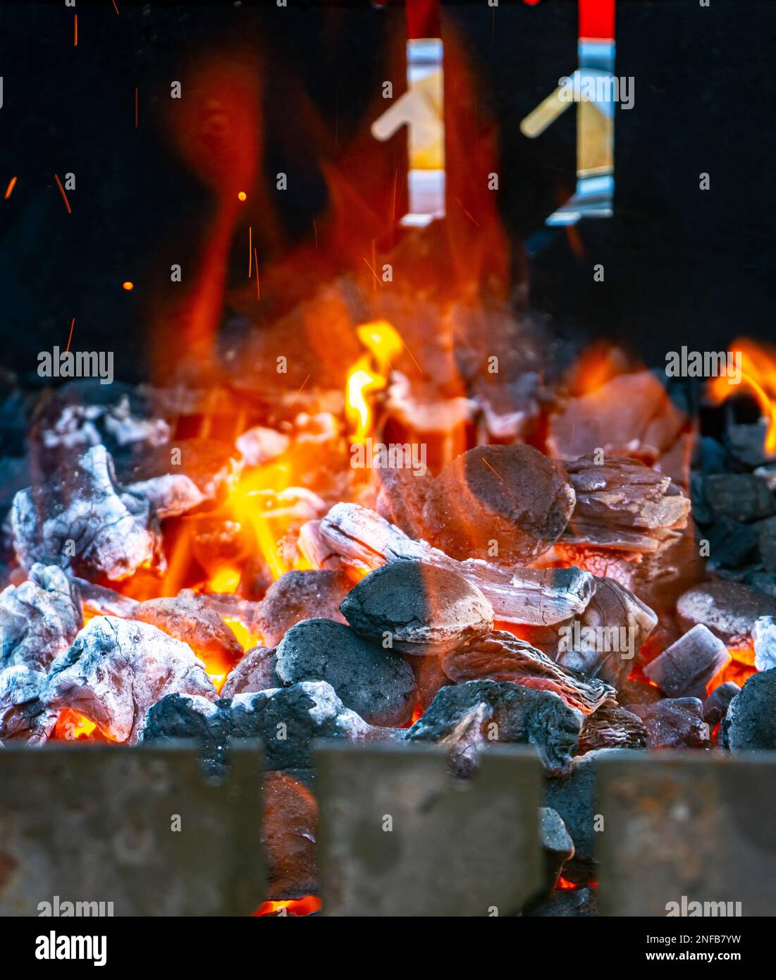 Carbone e brace che brucia a piena capacità al suo picco in un barbecue di metallo e fumo Foto Stock