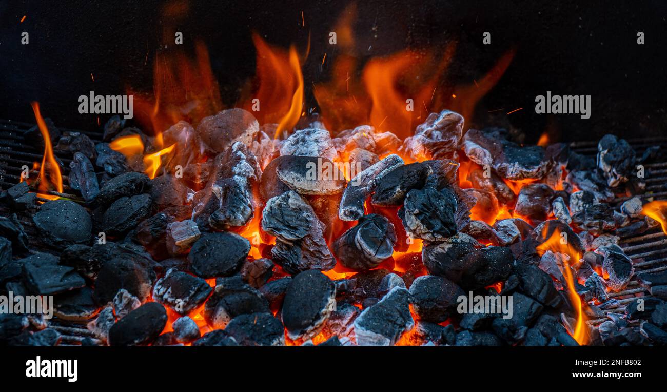 Carbone e brace che brucia a piena capacità al suo picco in un barbecue di metallo e fumo Foto Stock