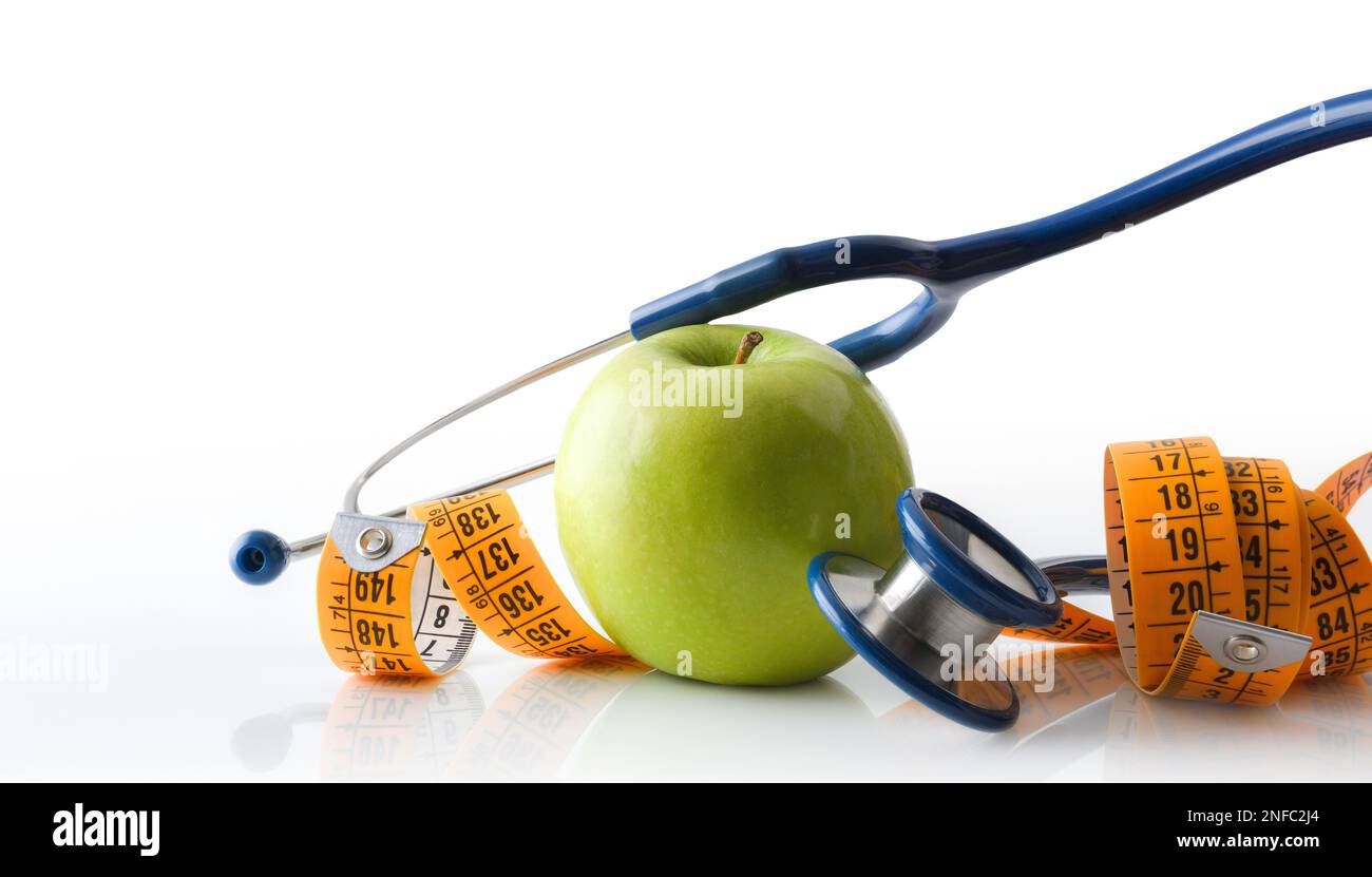 Apple, stetoscopio e metro a nastro si riflettono su un tavolo bianco e sfondo bianco isolato che rappresentano la salute, la nutrizione e il controllo del corpo. Vista frontale Foto Stock