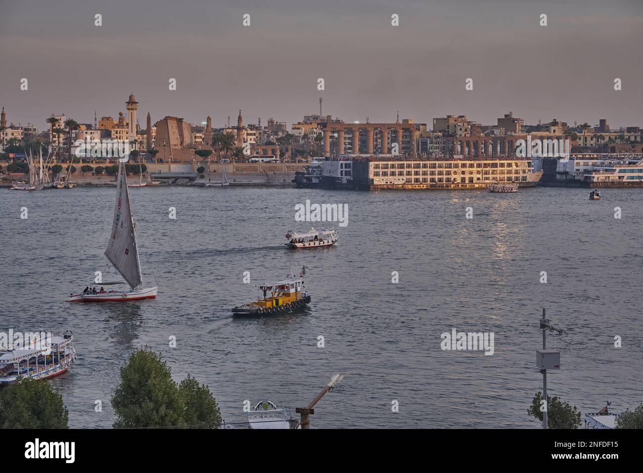 Luxor, Egitto tramonto girato dalla riva ovest mostrando il fiume Nilo con Felucche, navi da crociera e Luxor Tempio in riva est Foto Stock