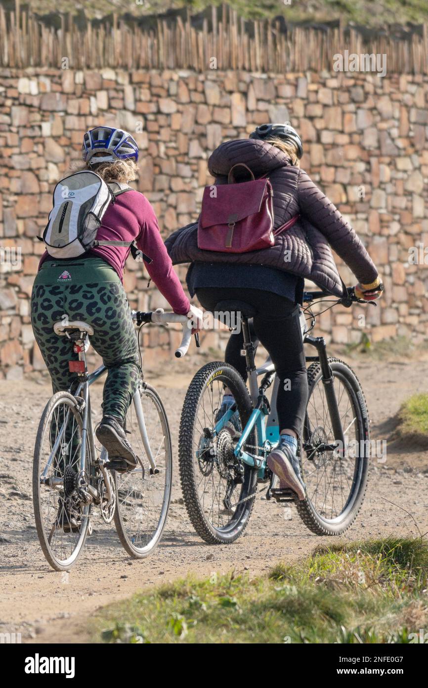 Due ciclisti femminili che pedalano lungo il sentiero costiero di Newquay, in Cornovaglia, nel Regno Unito. Foto Stock