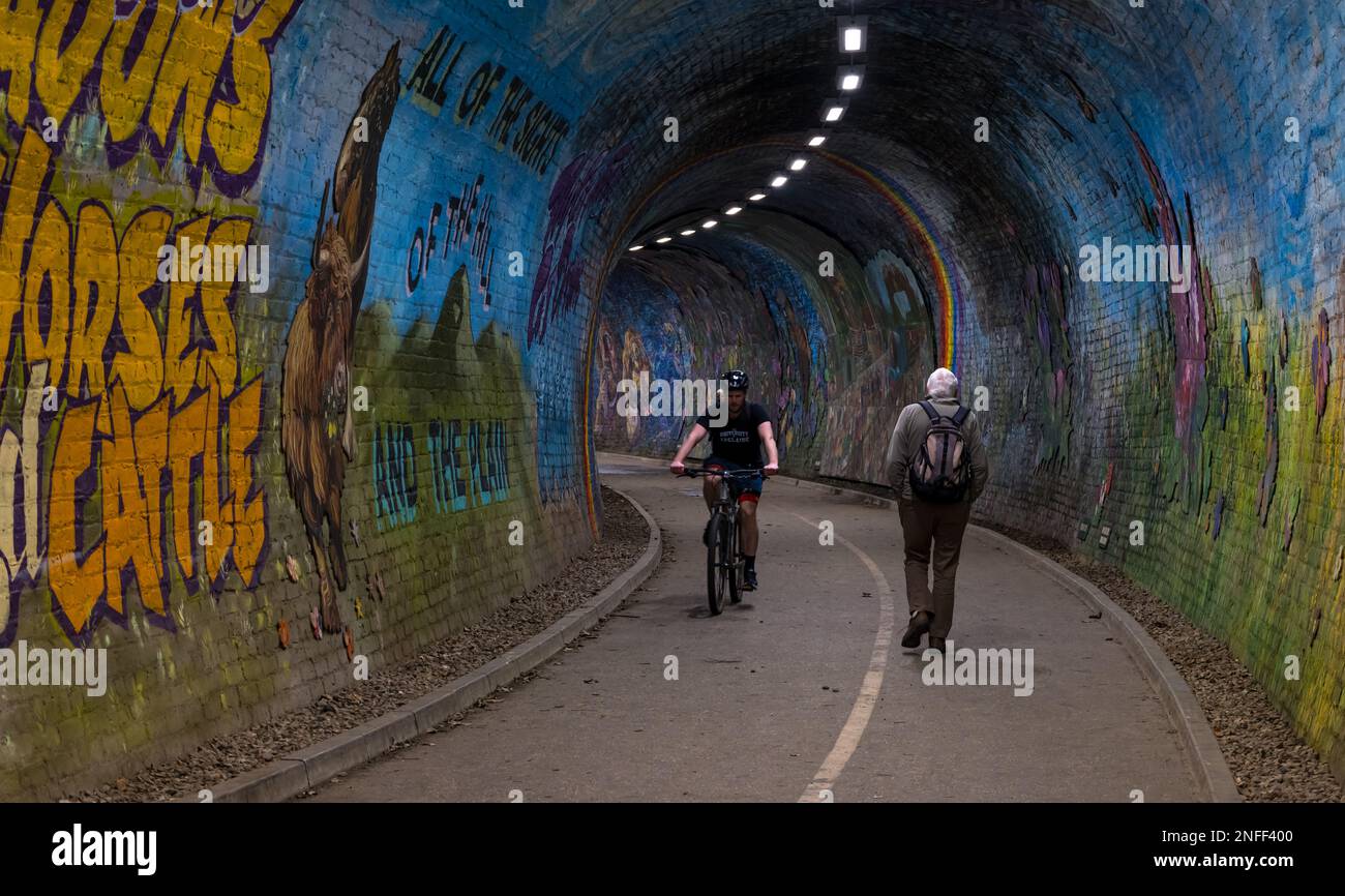 Uomo che cammina e ciclista nel tunnel ferroviario di Colinton, dipinto dall'artista Chris Rutterford, Edimburgo, Scozia, Regno Unito Foto Stock