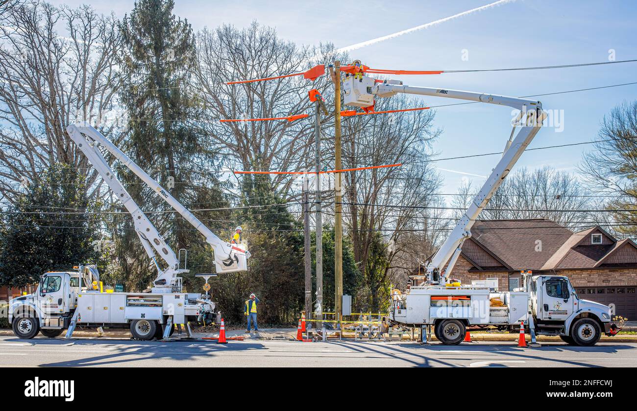 HICKORY, NC, USA-14 FEB 2023: Operai di servizi pubblici con due carrelli a benna che riparano le linee elettriche. Foto Stock