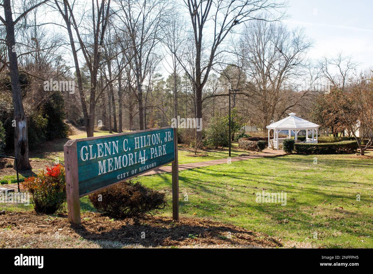 HICKORY, NC, USA-14 FEB 2023: Glenn Hilton City Park, cartello monumento e passeggiata in mattoni che conduce al gazebo bianco. Sole, cielo blu, giorno d'inverno. Foto Stock