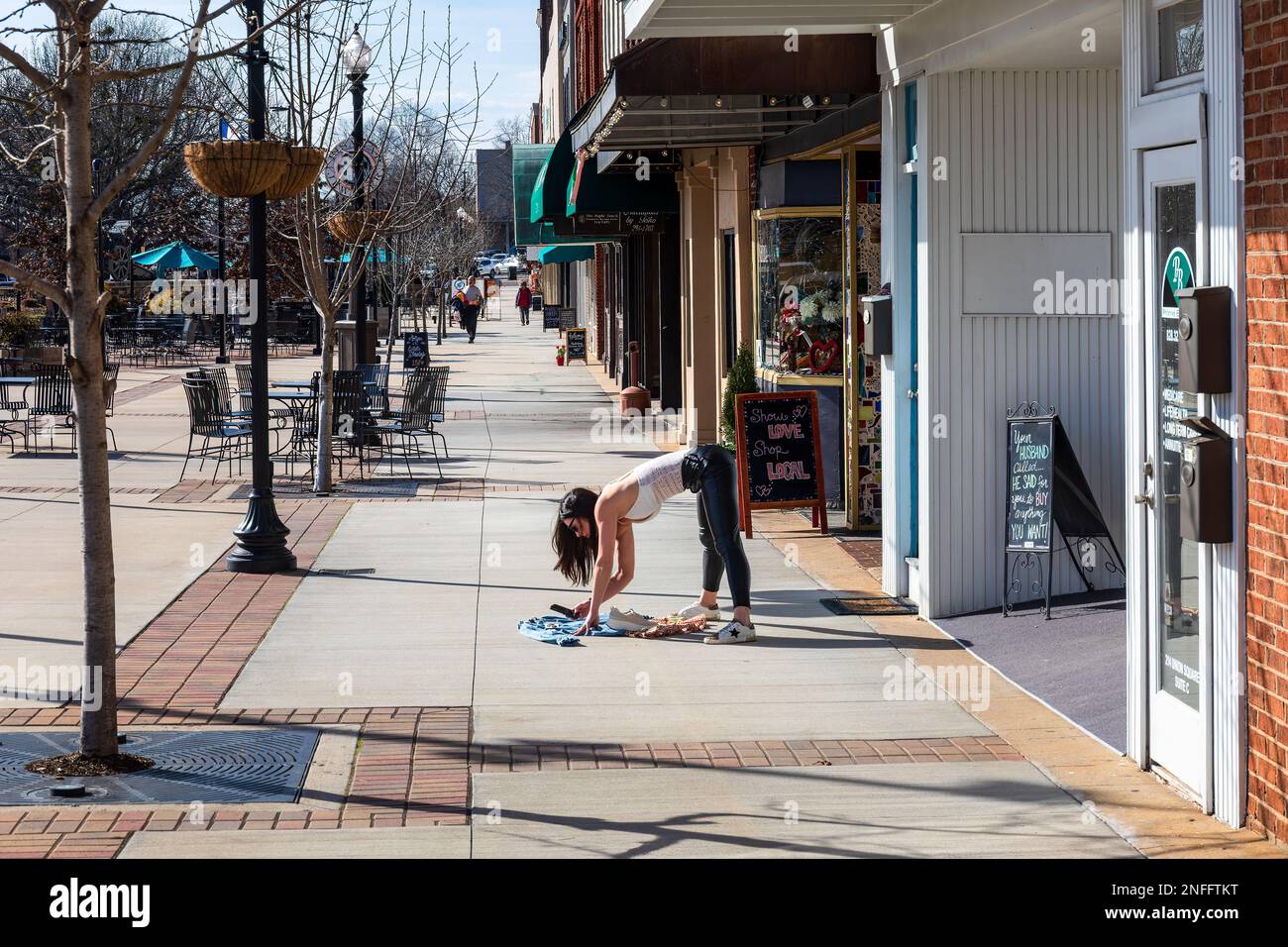 HICKORY, NC, USA-14 FEB 2023: Giovane donna che fotografa vestiti sul marciapiede soleggiato. Foto Stock