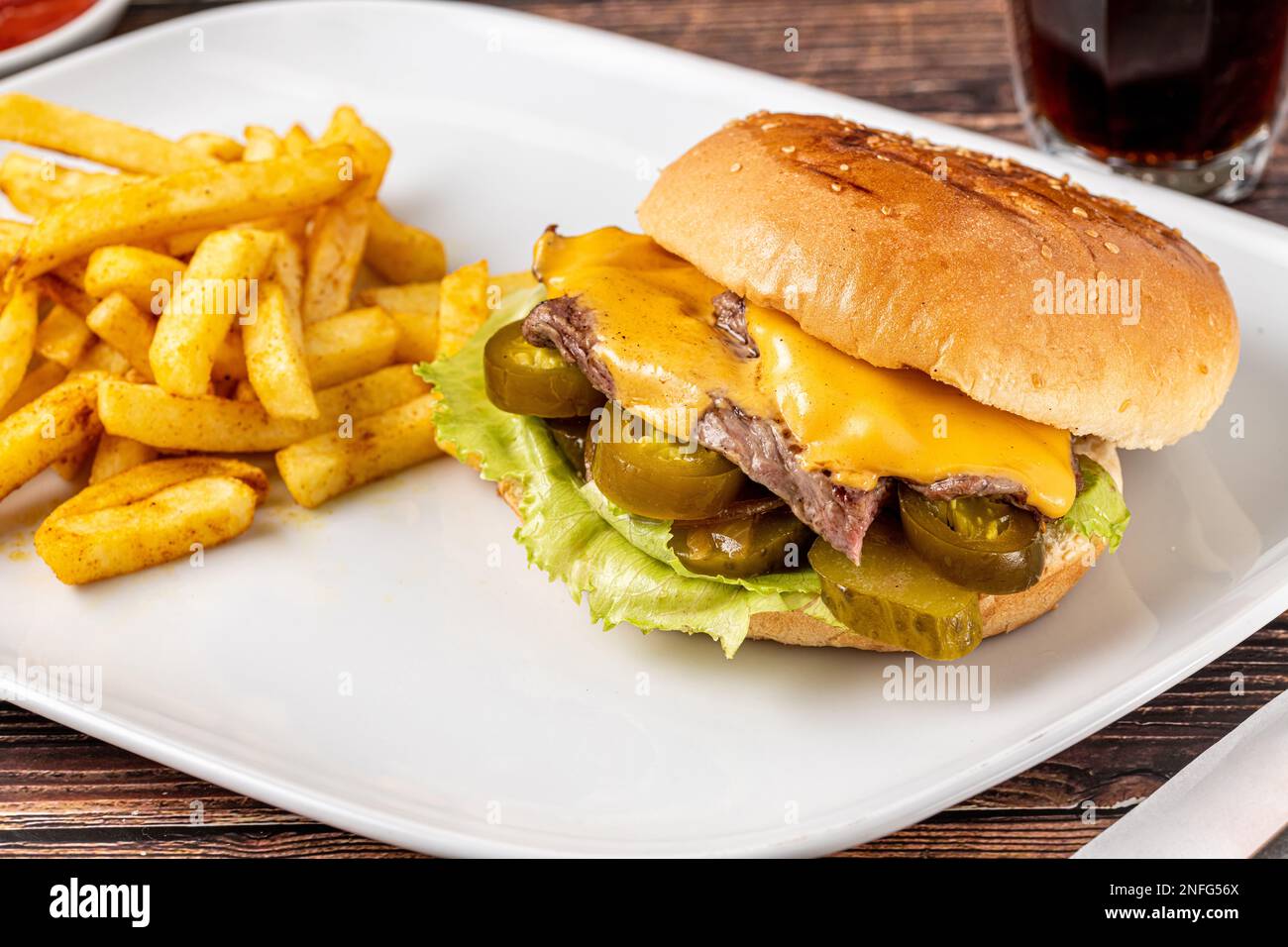 Delizioso hamburger di manzo con patatine fritte, anelli di cipolla e salse Foto Stock