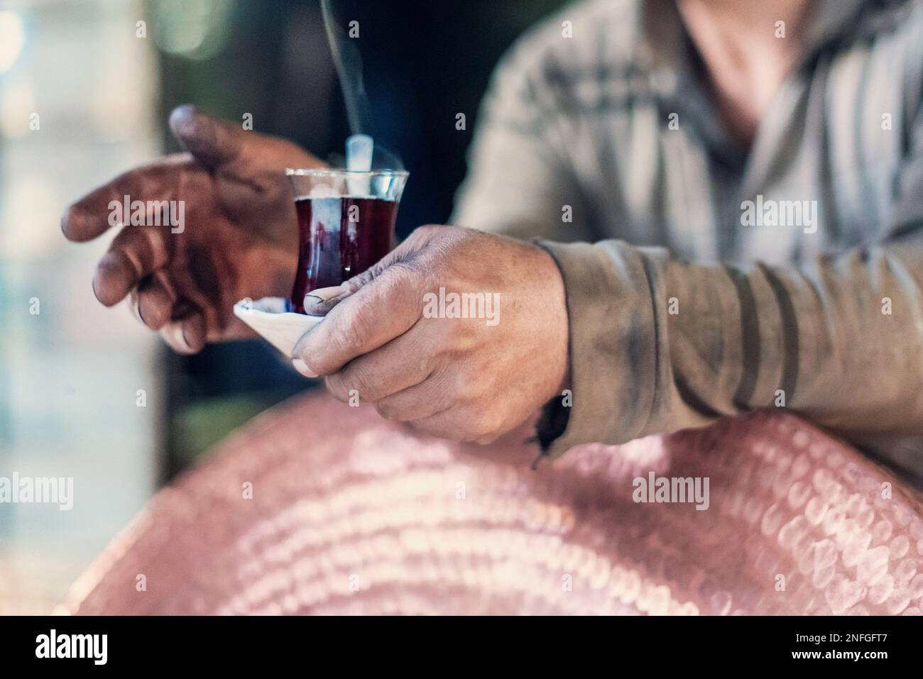 Una mano del lavoratore con il tè nero turco tradizionale nella città di Kahramanmarşa del paese della Turchia, primo piano, dettagli Foto Stock
