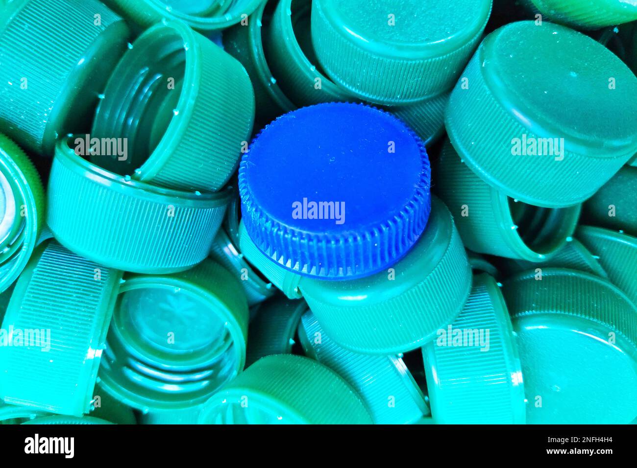 Tappo di plastica blu al centro dei tappi di plastica verdi. Foto Stock