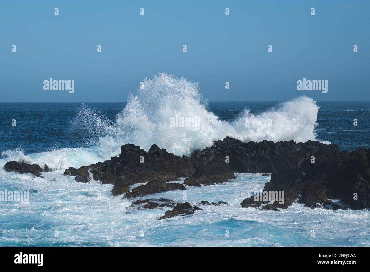le onde dell'oceano si schiantano sulle rocce durante il tempo ventoso Foto Stock