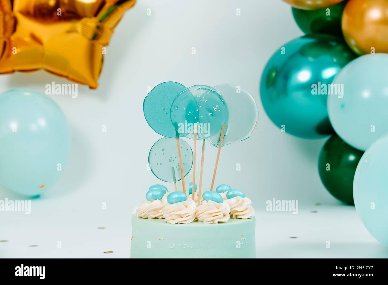 primo piano di una bella torta blu e alcuni palloncini di diversi colori e dimensioni formando una decorazione elegante per un compleanno di una festa di nozze o un bambino cak Foto Stock