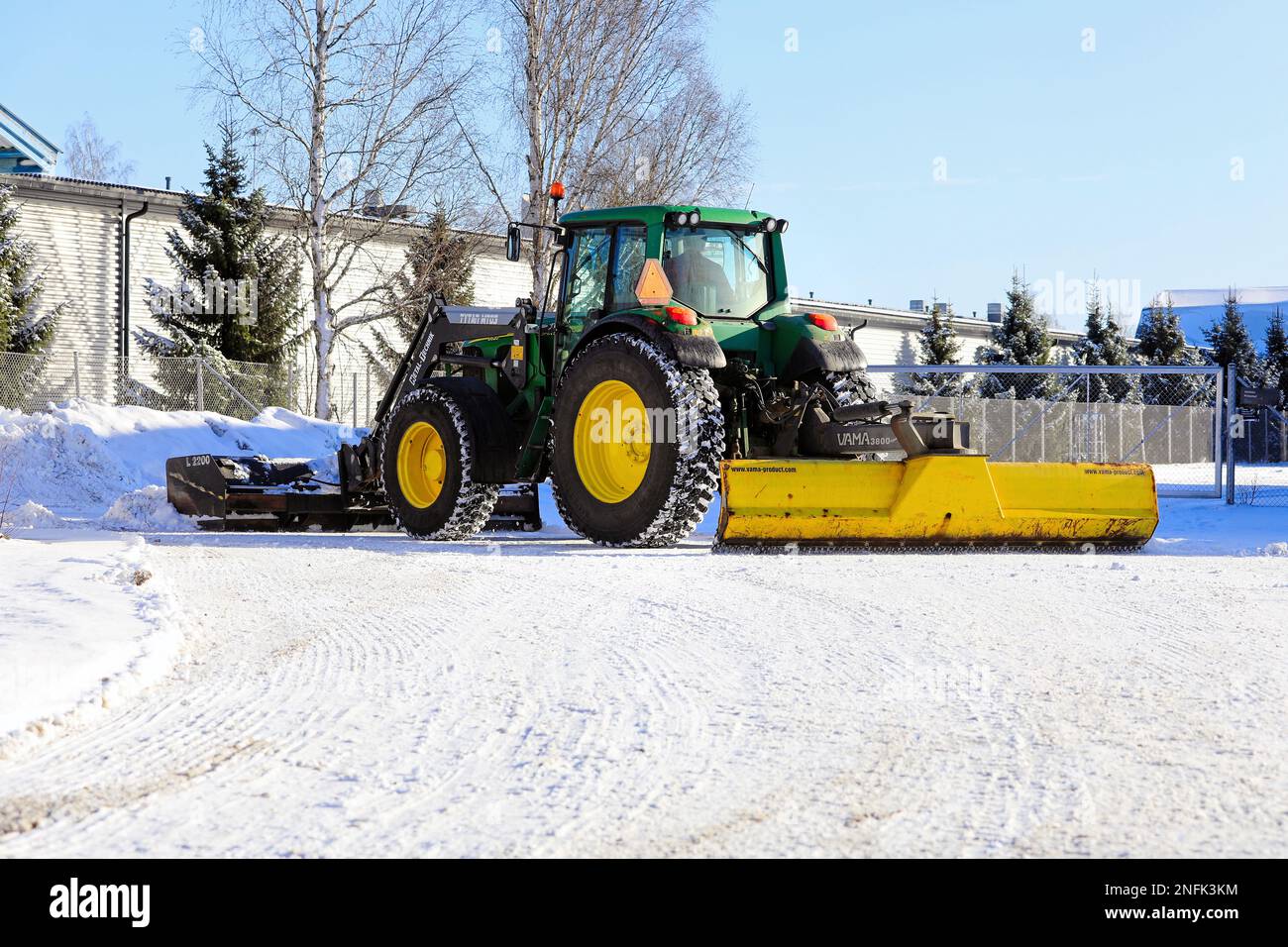 Rimozione della neve dall'area di parcheggio con trattore John Deere 6620 con spazzaneve e lama posteriore VAMA 3800. Salo, Finlandia. Febbraio 11, 2023. Foto Stock