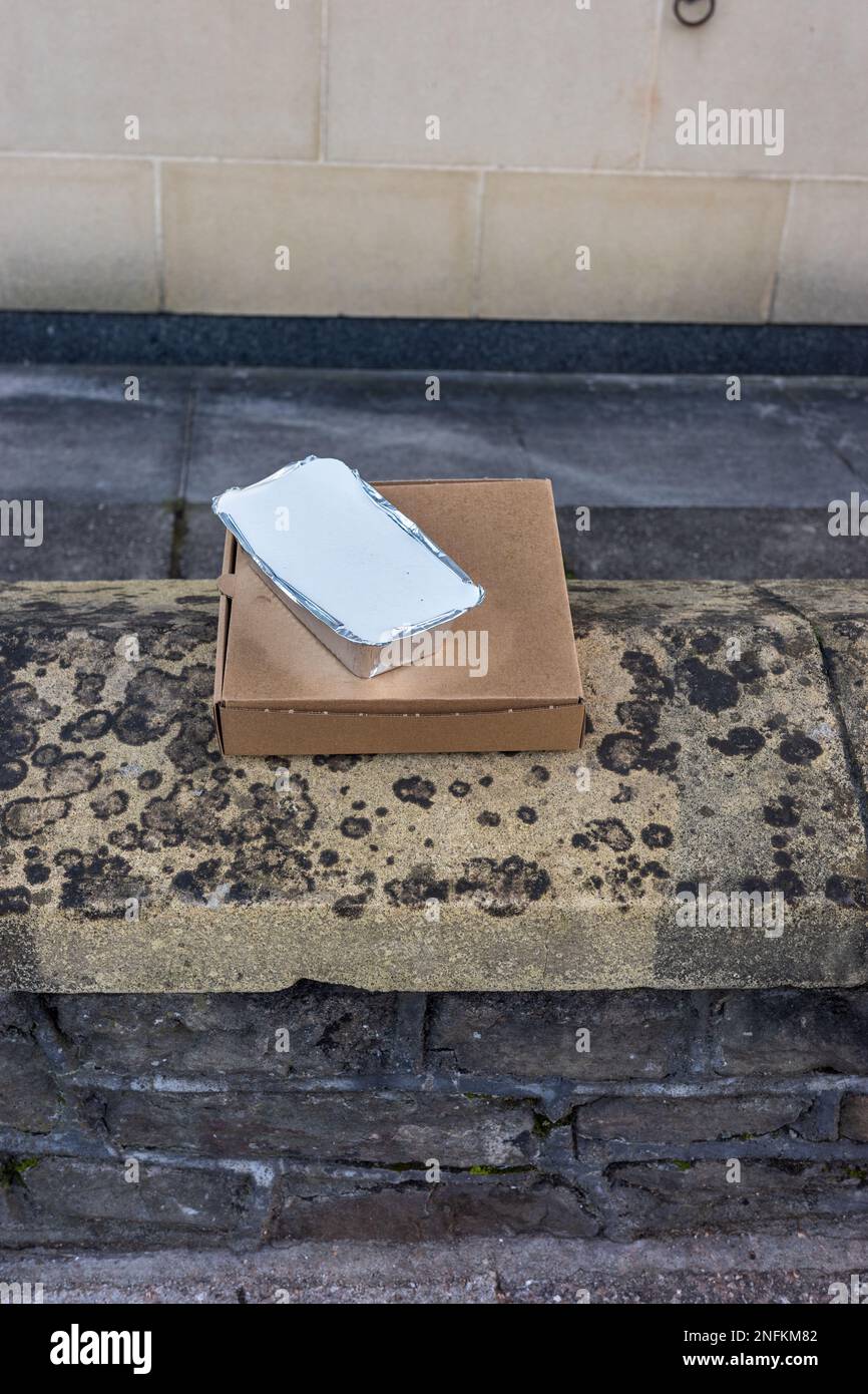 Scatola per pizza semplice da asporto e vassoio in alluminio su una parete in mattoni Foto Stock