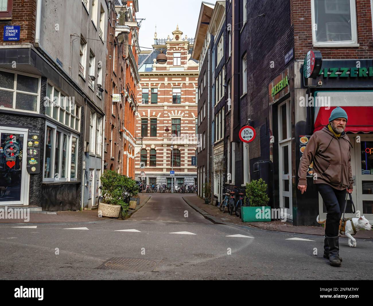 Amsterdam, Paesi Bassi. 15th Feb, 2023. Un uomo è visto camminare con il suo cane. Amsterdam è una delle città più belle, creative e ciclabili d'Europa. Ha un ottimo mix di atmosfera cosmopolita e dimensioni relativamente piccole, il che significa che ha un fascino simile a quello di un villaggio. Anche se è ancora freddo ma soleggiato, i turisti stanno già visitando la capitale olandese nei giorni feriali. I luoghi più visitati sono di solito piazza Dam, il centro della città, i musei e i canali. (Foto di Ana Fernandez/SOPA Images/Sipa USA) Credit: Sipa USA/Alamy Live News Foto Stock