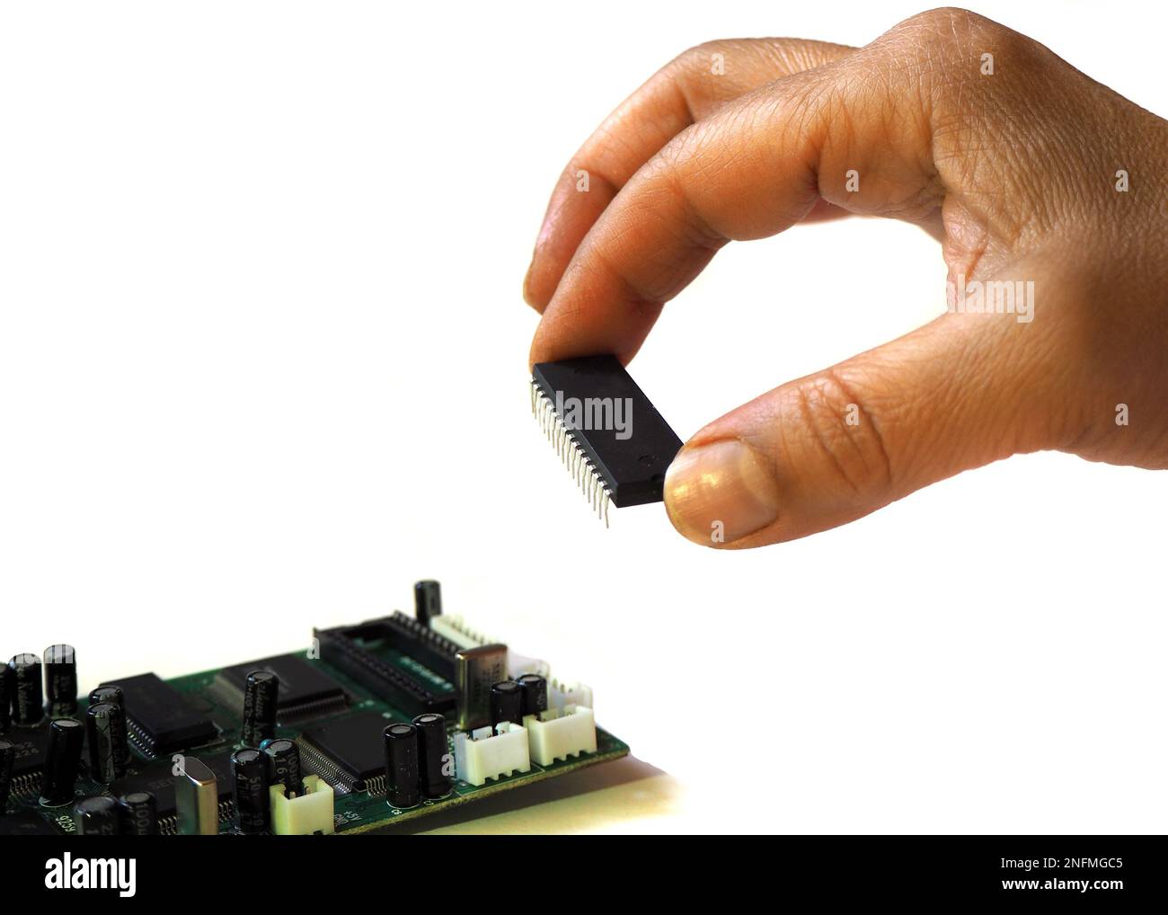 Le dita collocano il chip. Circuito integrato di tenuta della mano su sfondo bianco inclinato. Foto Stock