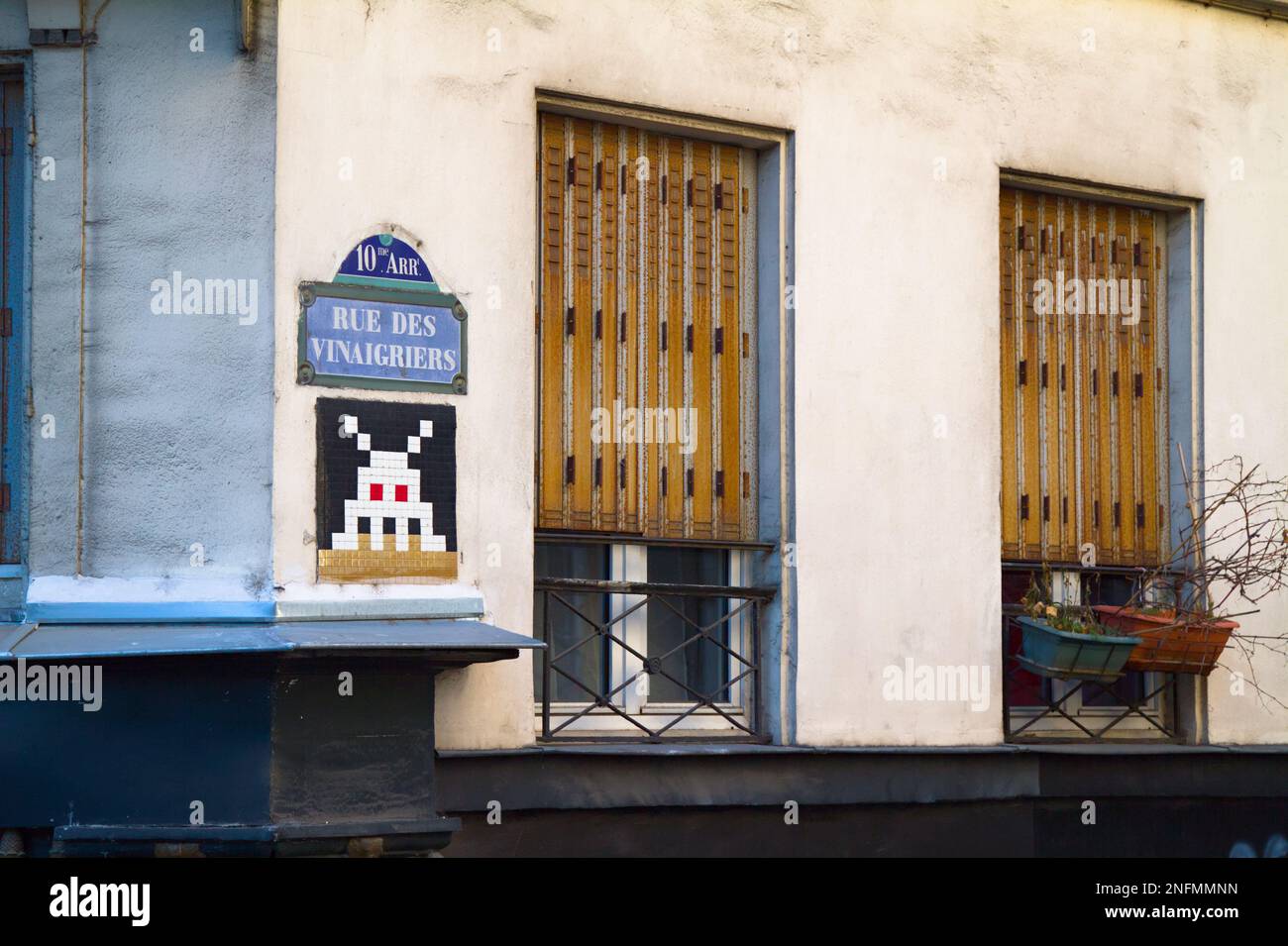 Street View dell'angolo di Rue des Vinaigriers con Uno spazio Invader Tile Mosaic, Graffiti e Una finestra con persiane, Parigi Francia Foto Stock