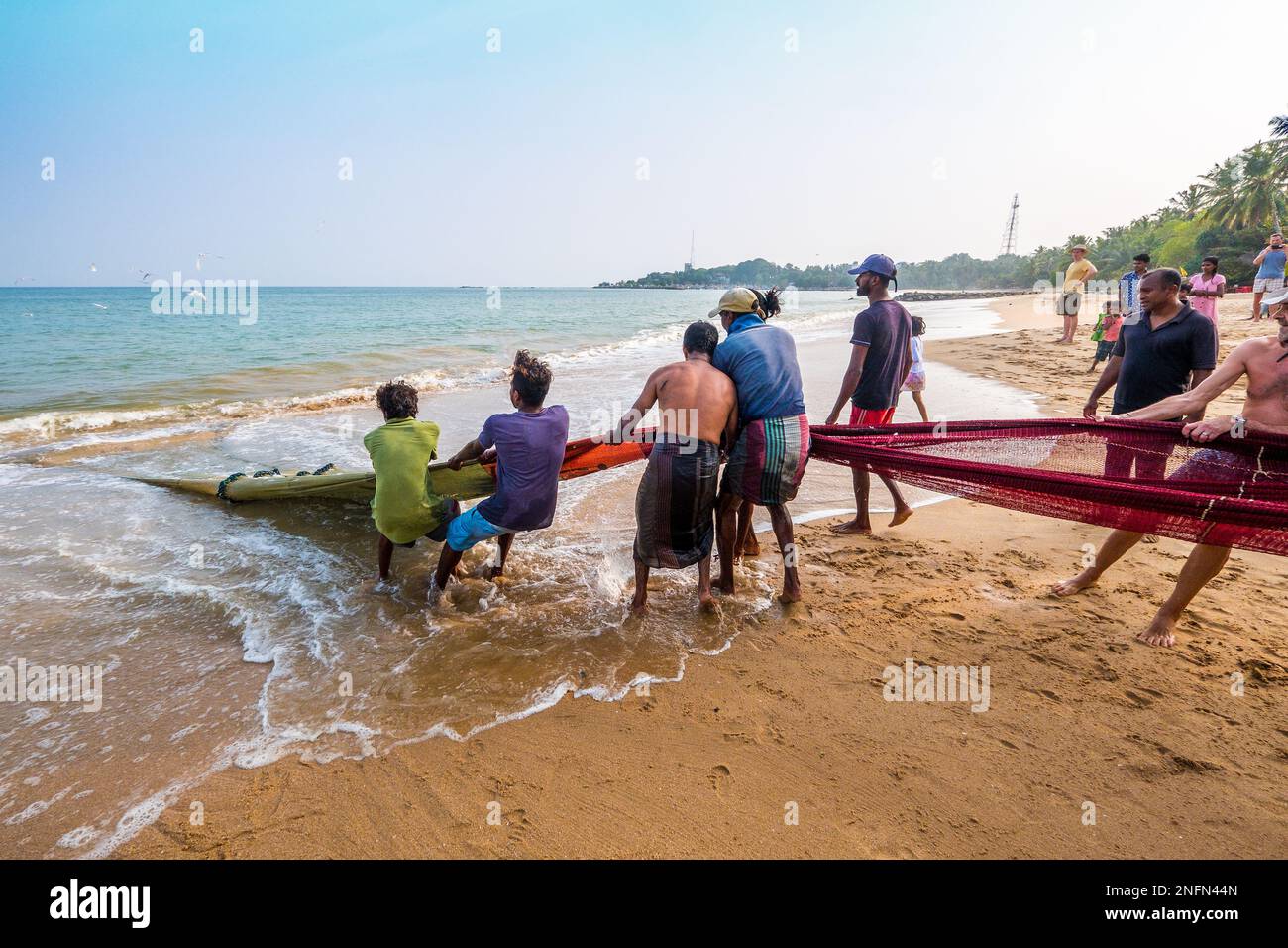 Pescatori che trasportano in una rete sulla spiaggia di Tangalle sulla costa meridionale dello Sri Lanka Foto Stock