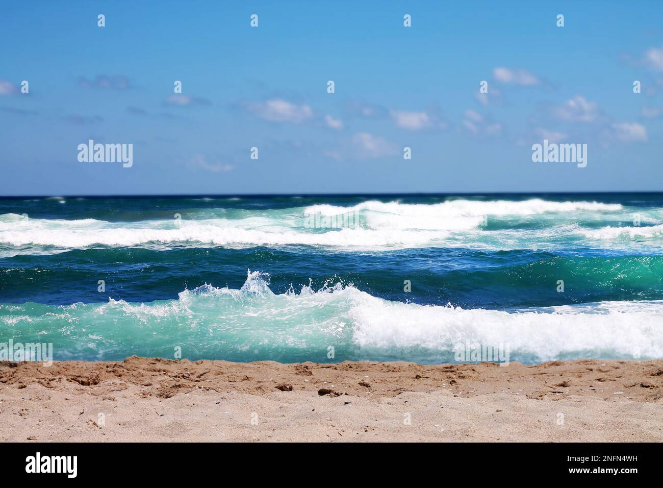 Vista delle onde sul mare e della spiaggia di sabbia vuota da vicino. Foto Stock