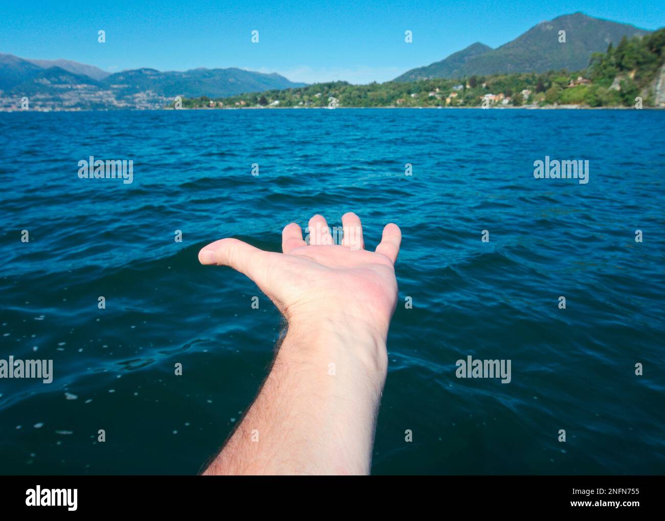 Il braccio maschile si allunga verso l'acqua, il lago maggiore, il Piemonte, l'Italia Foto Stock