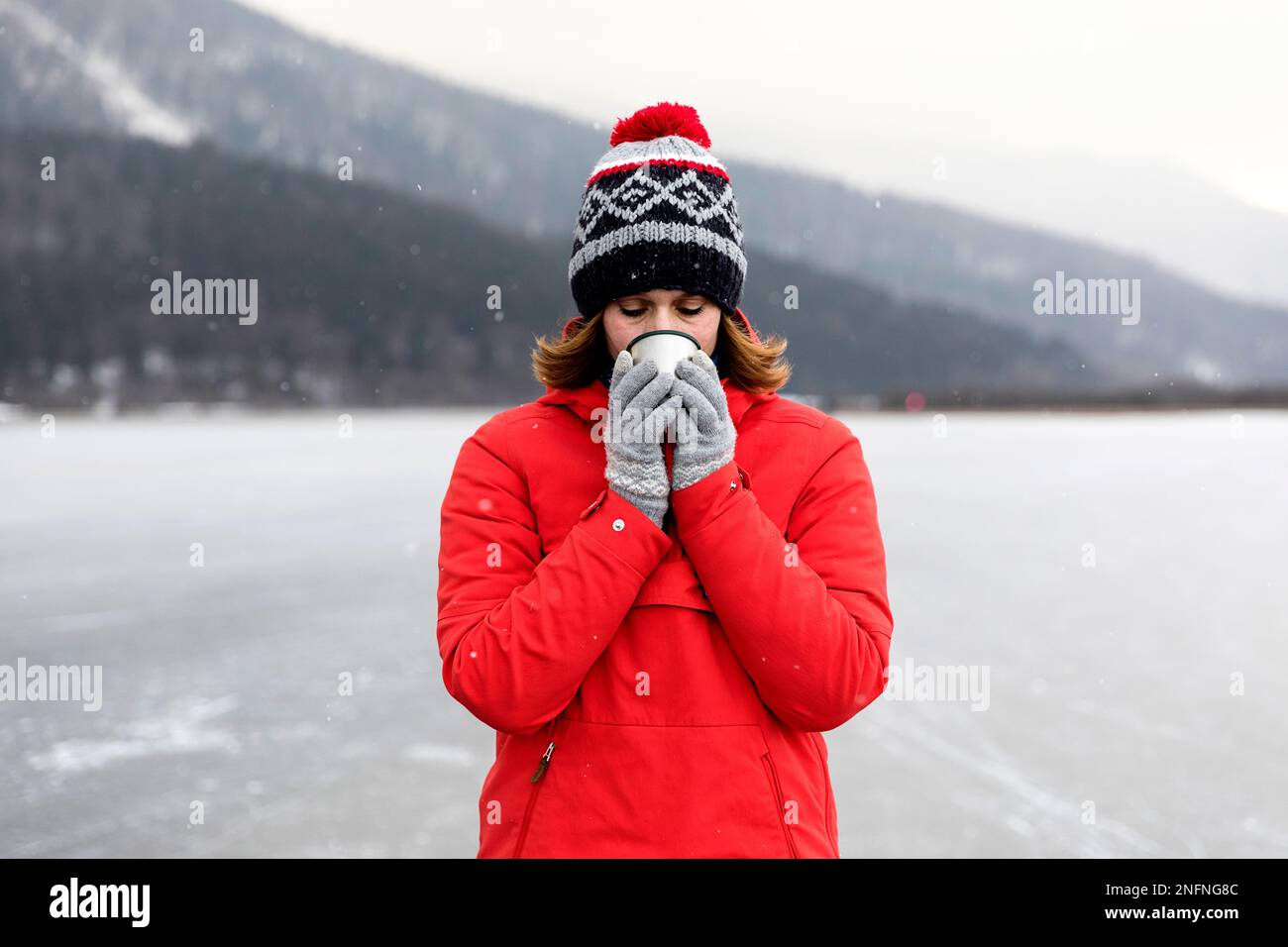 Donna che beve il tè caldo dopo il pattinaggio su ghiaccio su un lago ghiacciato, Cerknica lago, Slovenia Foto Stock