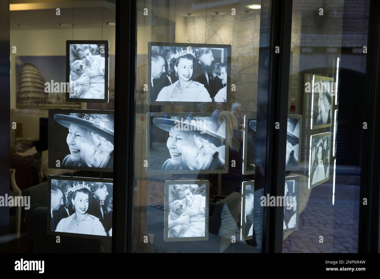 Le persone in coda per la sdraiata si riflettono in una vetrina dove vengono esposti a Londra i ritratti della defunto Regina Elisabetta II. Foto Stock