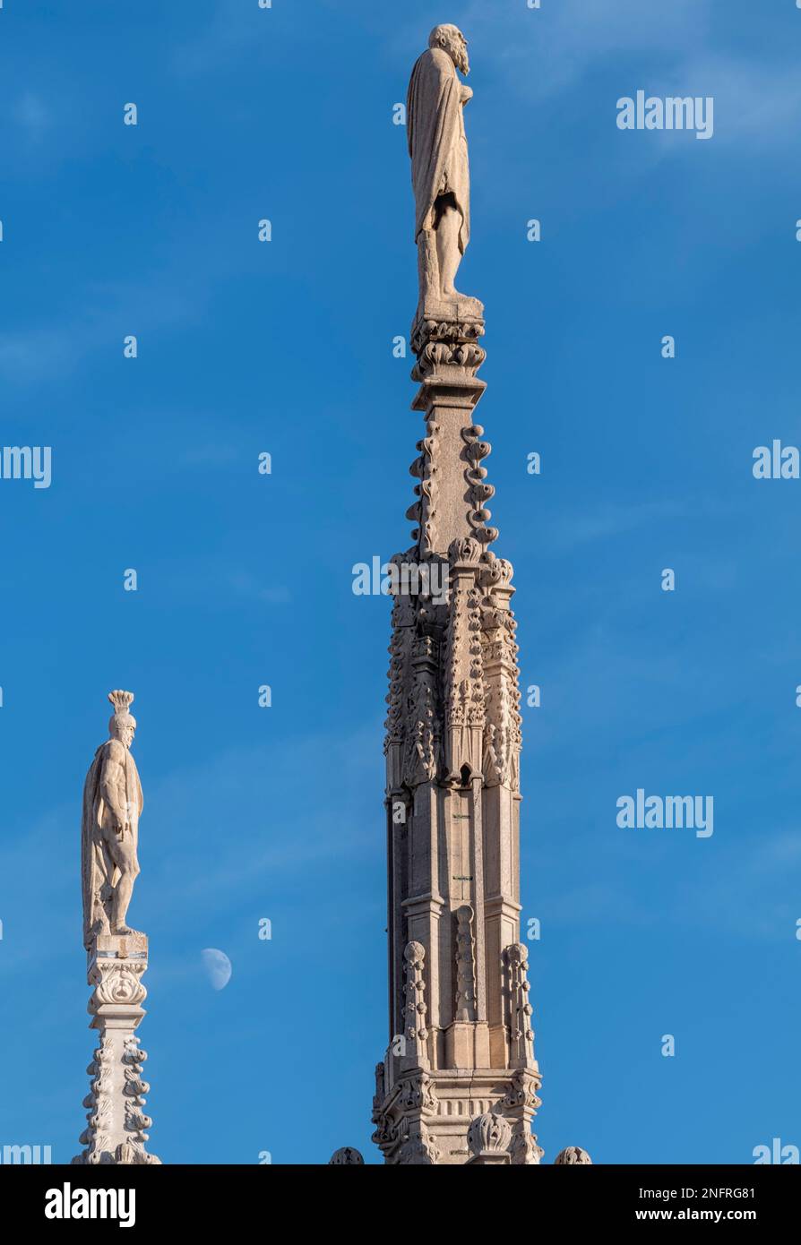 Milano Italia. Statue sulle guglie del Duomo e luna Foto Stock