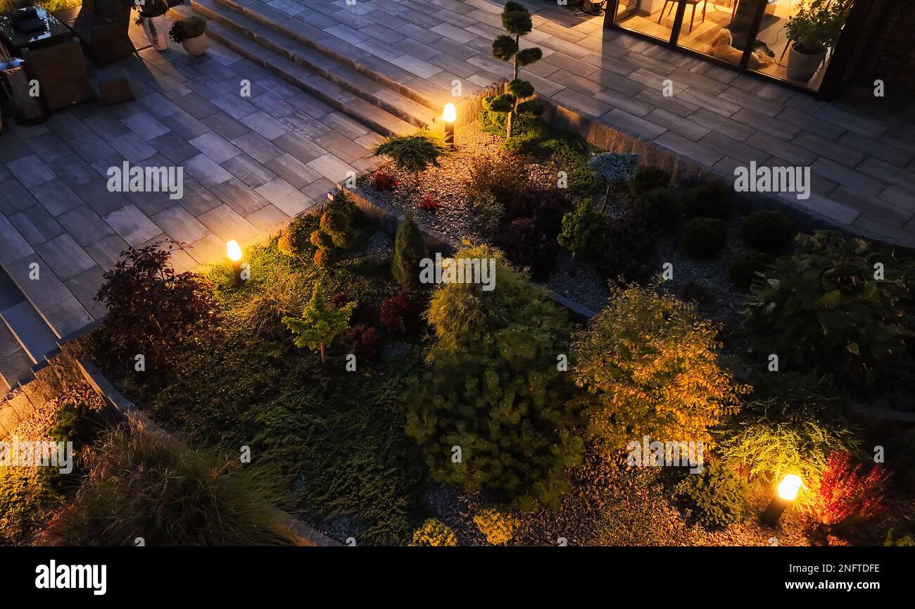 Curato professionalmente e ben organizzato giardino cortile illuminato con lampade a Bollard esterni. Vista aerea, sera. Foto Stock