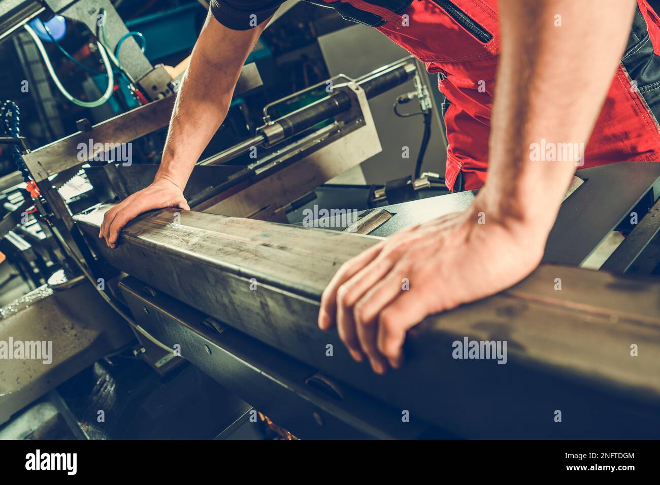 Operatore di macchine industriali professionale che taglia profili metallici con utensile elettrico a nastro. Tema tecnologia di produzione. Foto Stock