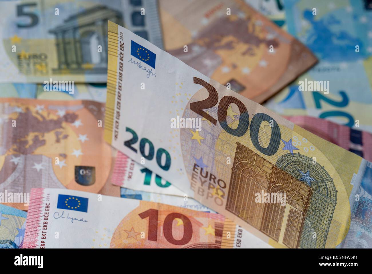 Una pila di banconote sul tavolo. Duecento euro di carta moneta in primo piano. Banconote miste in euro in background. Foto Stock
