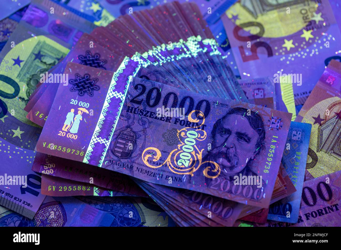 Per verificare l'autenticità del denaro. 20.000 banconote HUF in luce UV, banconote in euro sullo sfondo. L'immagine potrebbe contenere rumore e grana. Foto Stock