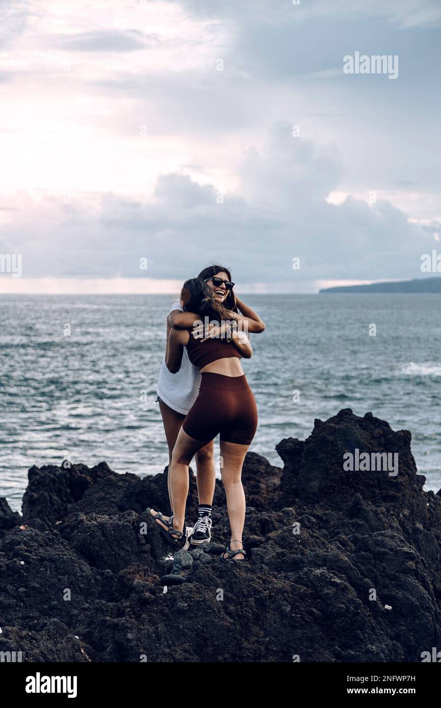 Due amici femminili si abbracciano in piedi su una roccia. Addio. Amicizia. Vacanza. Abbraccio Foto Stock