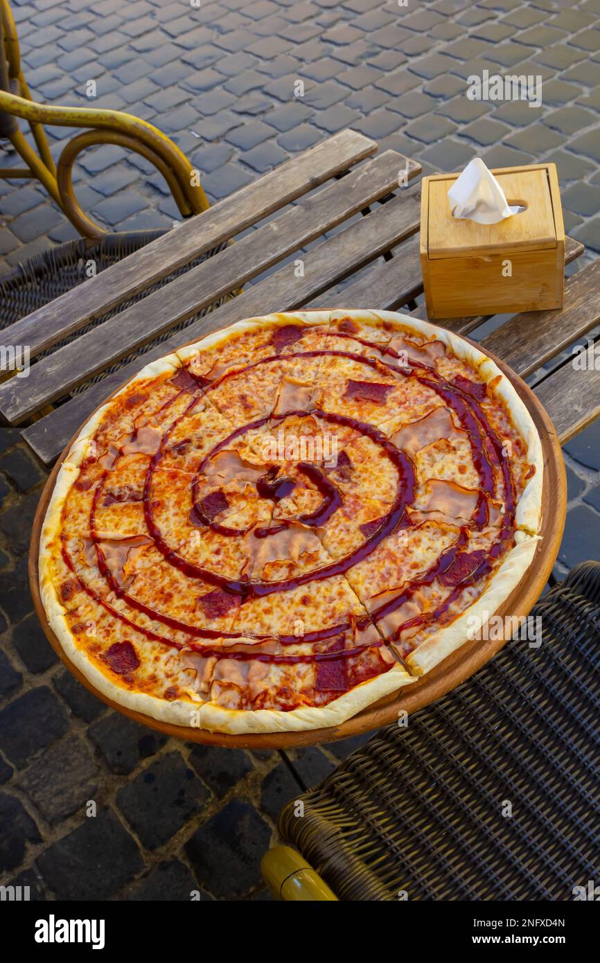pizza su un tavolo di legno di un caffè di strada in un giorno d'estate. Foto Stock