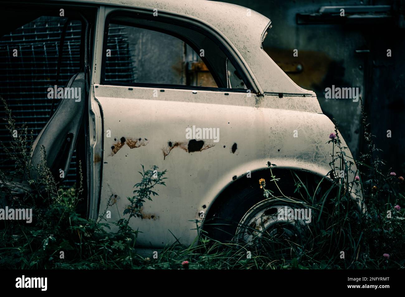 Una bella vista di una vecchia macchina bianca abbandonata rotta in una zona verduosa Foto Stock
