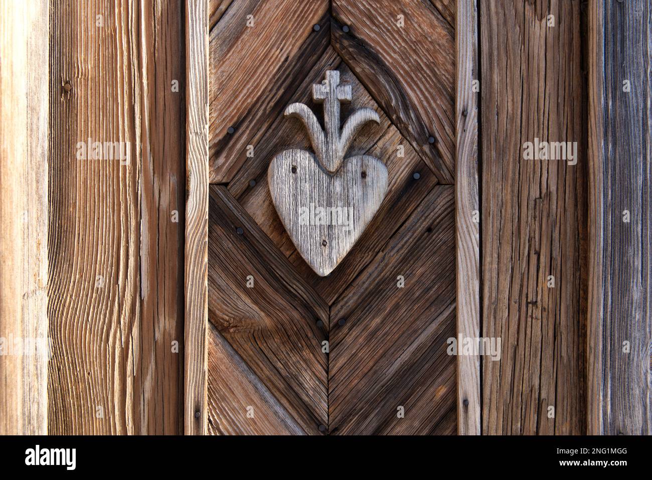 vecchio hart in legno con disegno a croce scolpito sulla parete del santuario lungo la strada Foto Stock