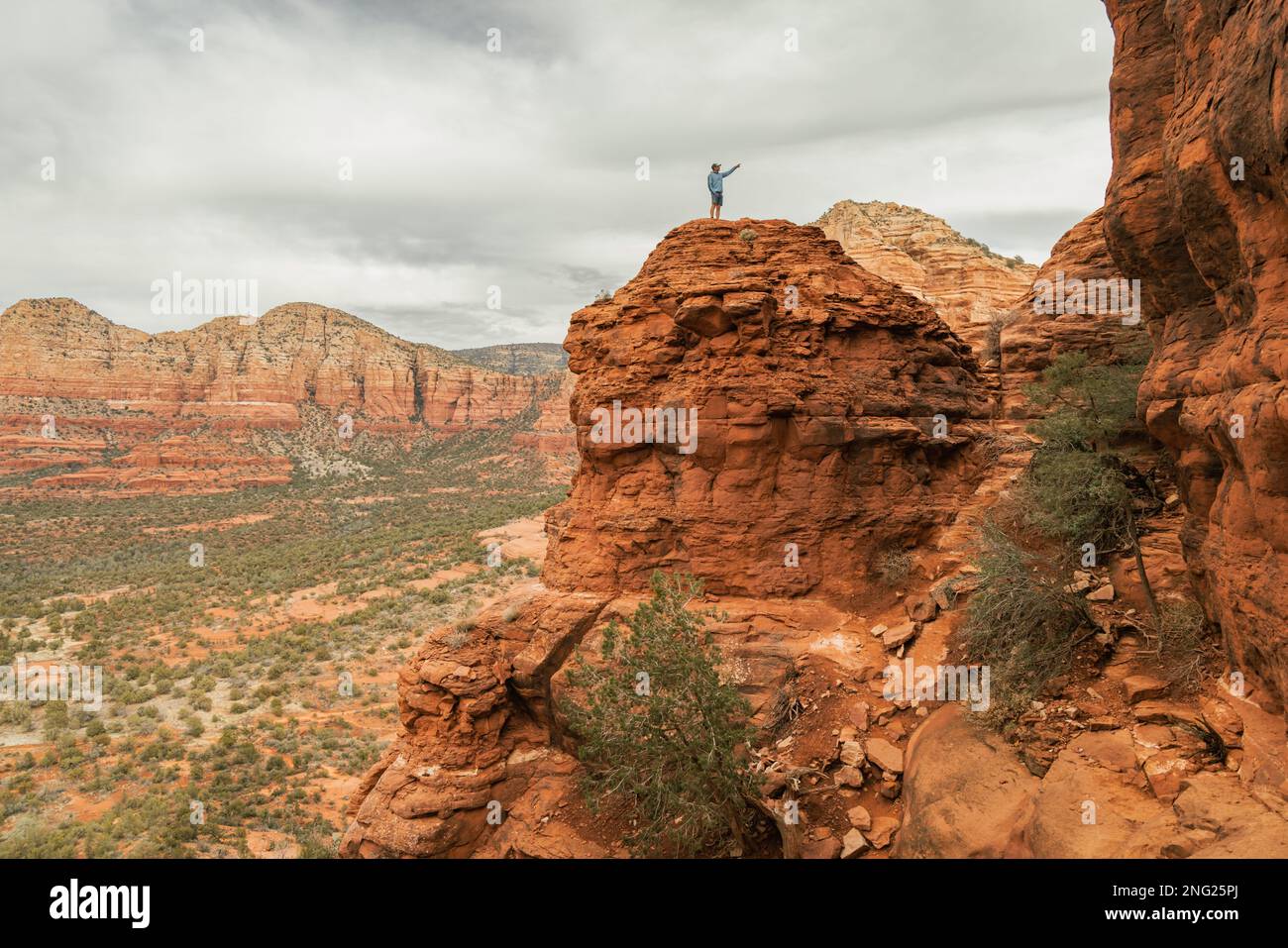 Uomo escursionista in piedi su Bell Rock con incredibili vedute all'interno della foresta nazionale di coconino a Sedona Arizona USA contro sfondo nuvoloso bianco. Foto Stock