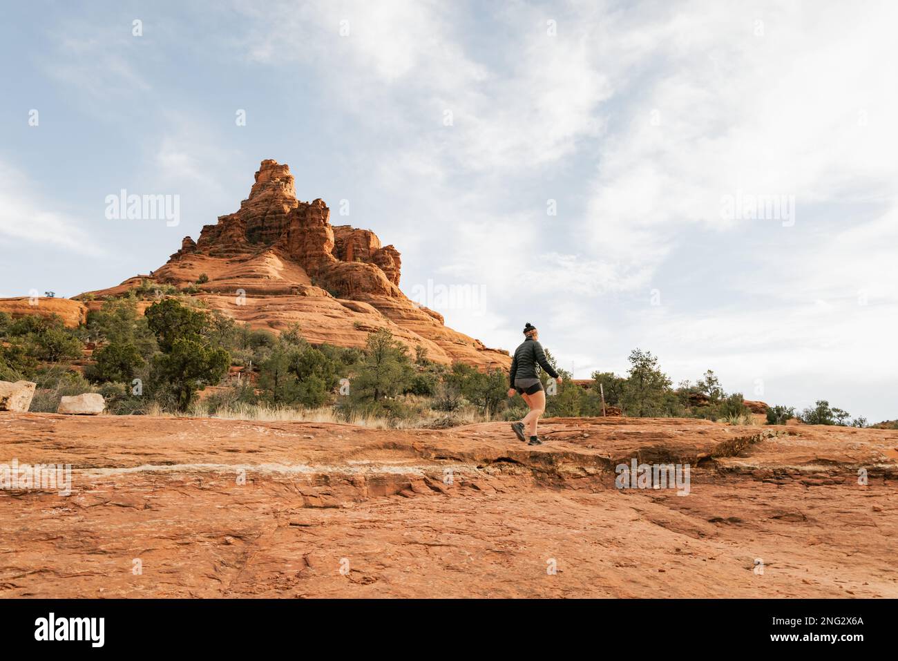 Donna escursionista in piedi sul percorso Bell Rock in formazioni di roccia rossa all'interno della foresta nazionale di coconino a Sedona Arizona USA contro sfondo nuvola bianca. Foto Stock