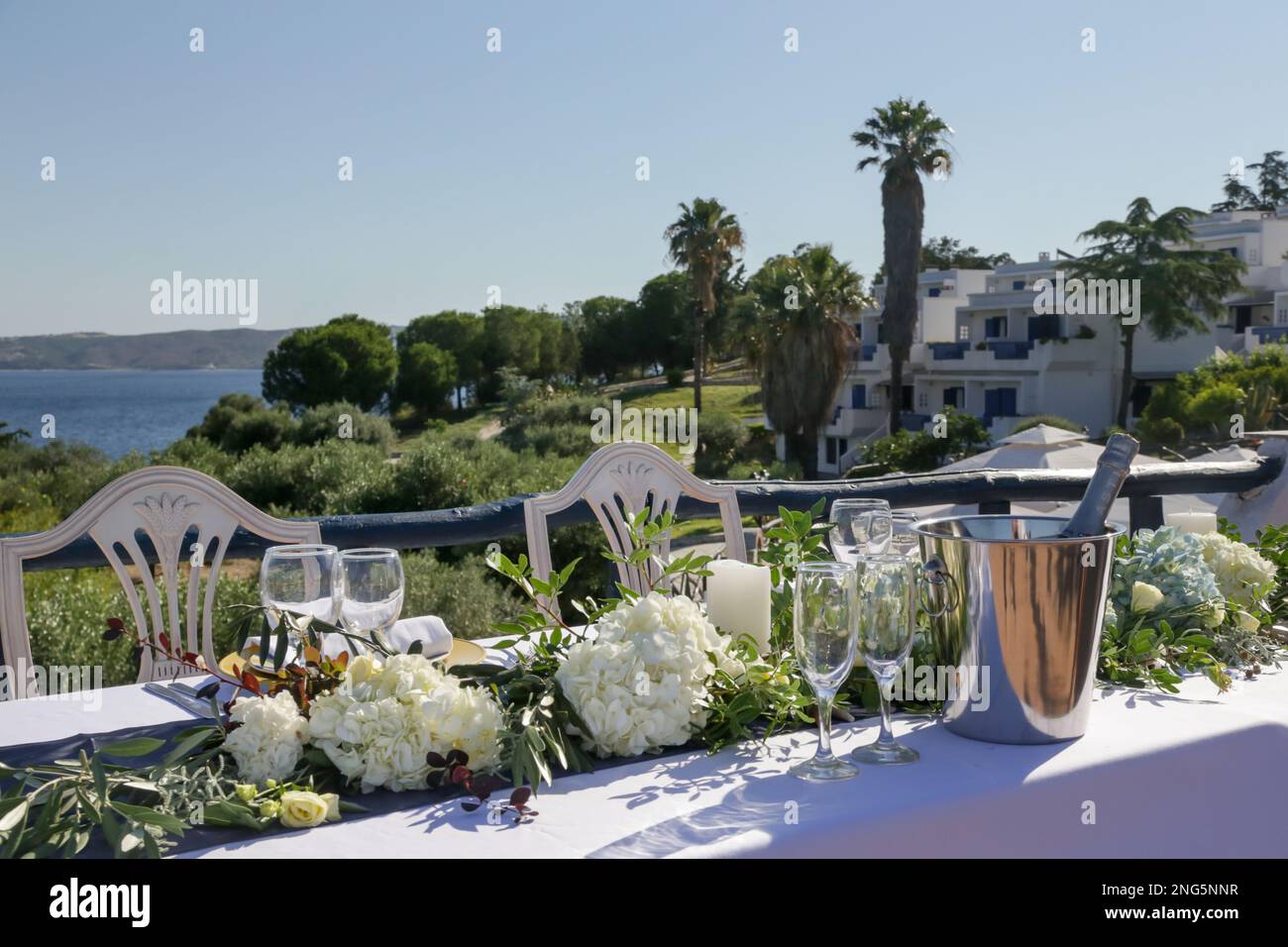 Elegante tavolo decorato con fiori bianchi e foglie verdi centrotavola e panno di lino bianco per un fidanzato, ricevimento di nozze o altro Foto Stock