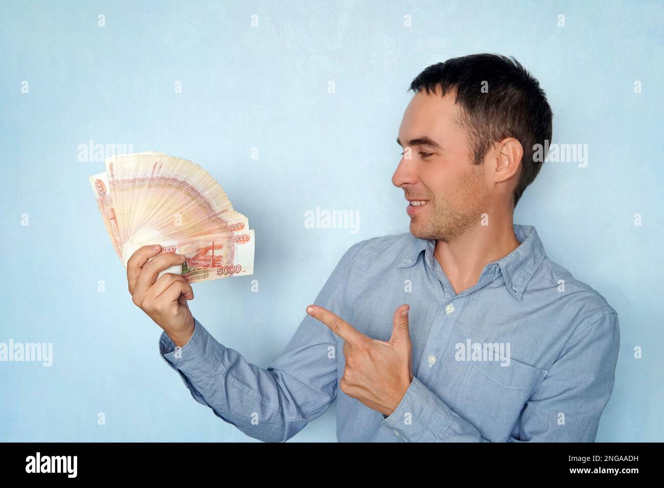 Giovane uomo d'affari seduto in un con un ventilatore di banconote di rubli, uno sguardo pazzo di gioia. Un incredibile guadagno nella vita della gente comune. un grande wad di m Foto Stock