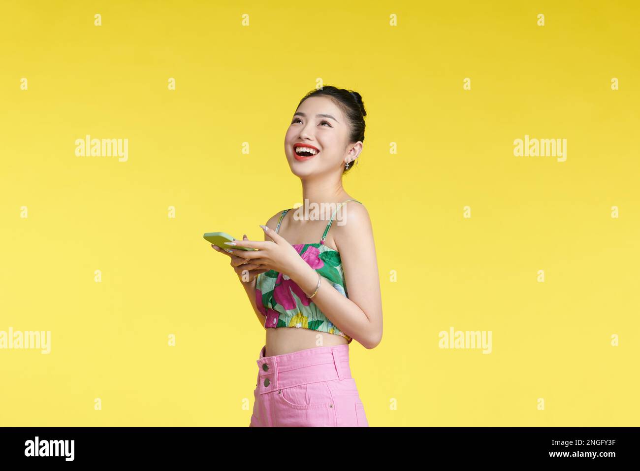 Foto di bella donna tenere telefono cellulare beaming sorriso eccitato isolato su sfondo giallo Foto Stock