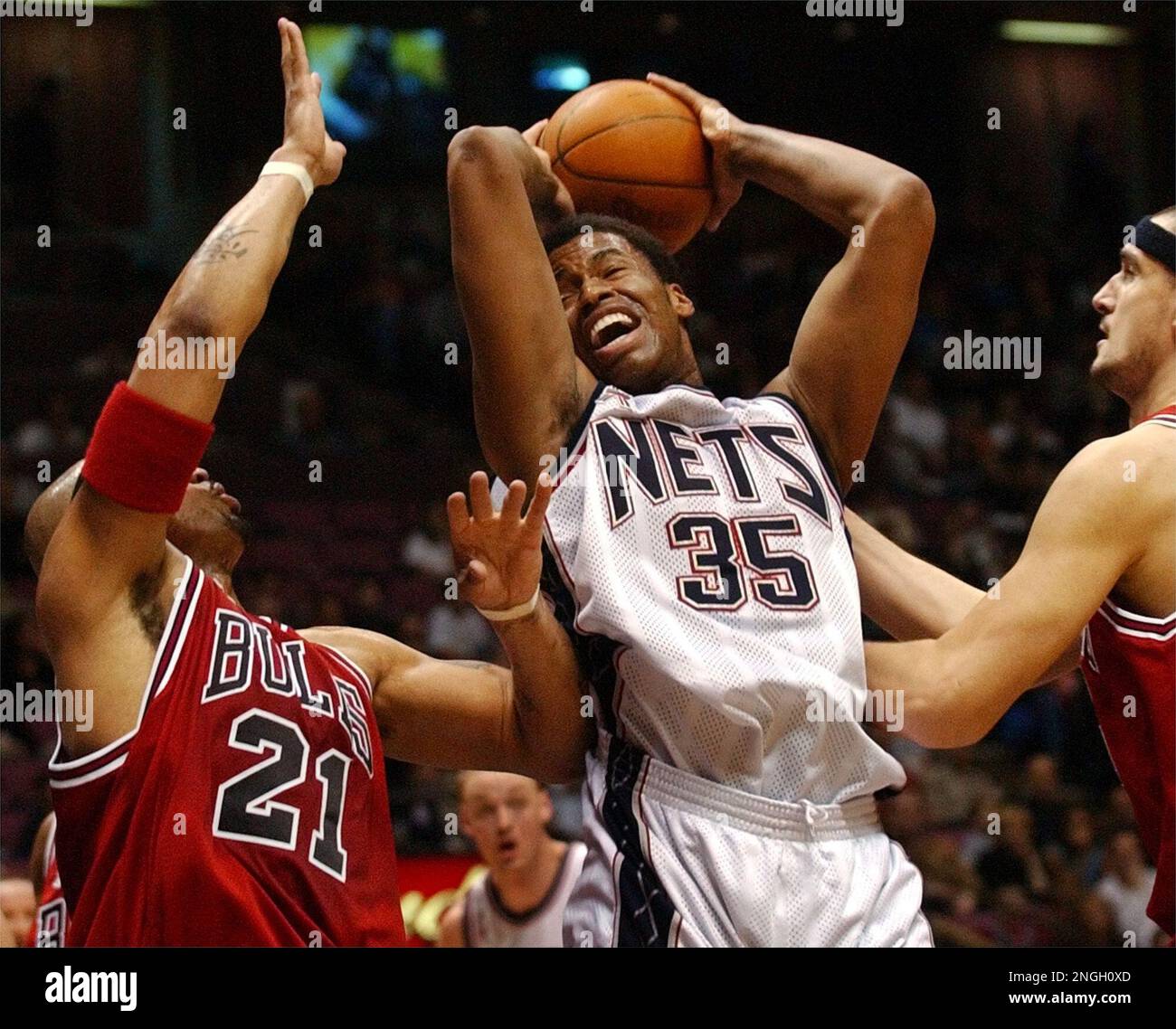 New Jersey Nets' Jason Collins (35) comes down with a rebound between Chicago Bulls Marcus Fizer (21) and Dalibor Bagaric during the first quarter Sunday, March 3, 2002, in East Rutherford, N.J. Collins led the Nets with 17 points and 12 rebounds as they beat the Bulls 92-84. (AP Photo/Bill Kostroun) Foto Stock