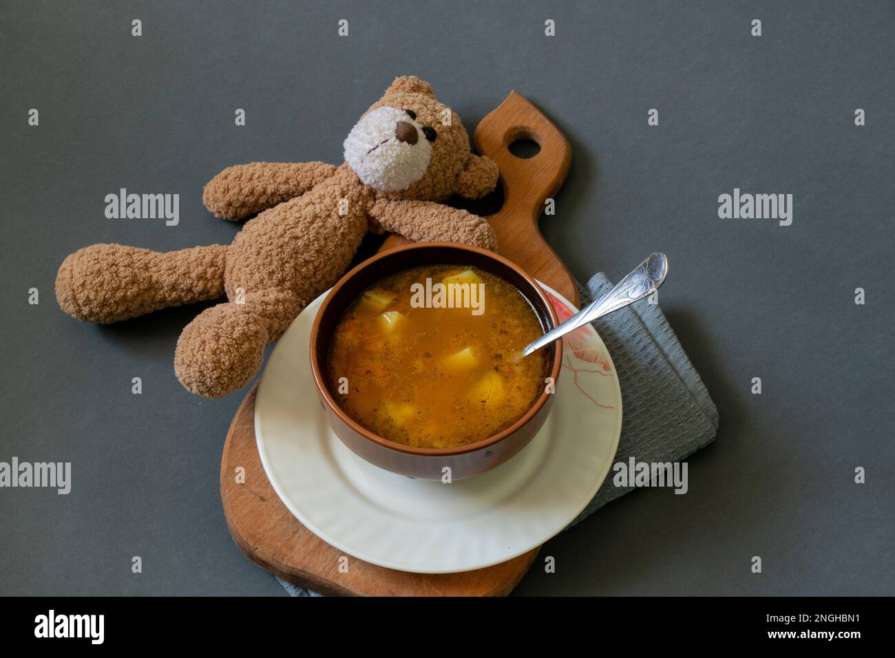 orsacchiotto e un piatto di zuppa accanto ad un buio Foto Stock