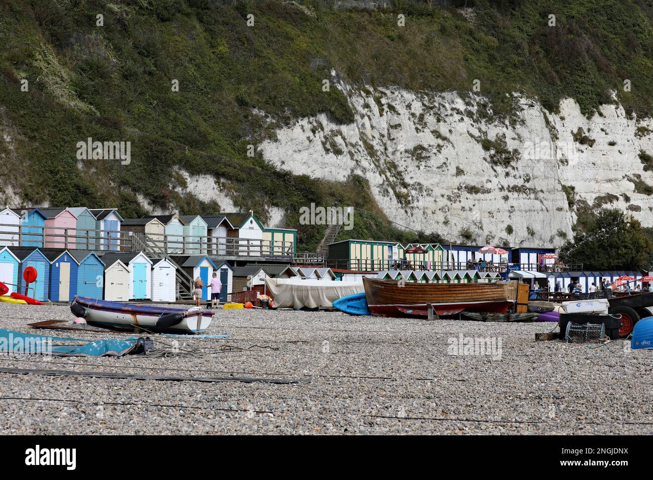 Sulla spiaggia nel villaggio di pescatori di Beer in Devon, Inghilterra. La spiaggia di ciottoli ospita capanne e barche da pesca. Foto Stock