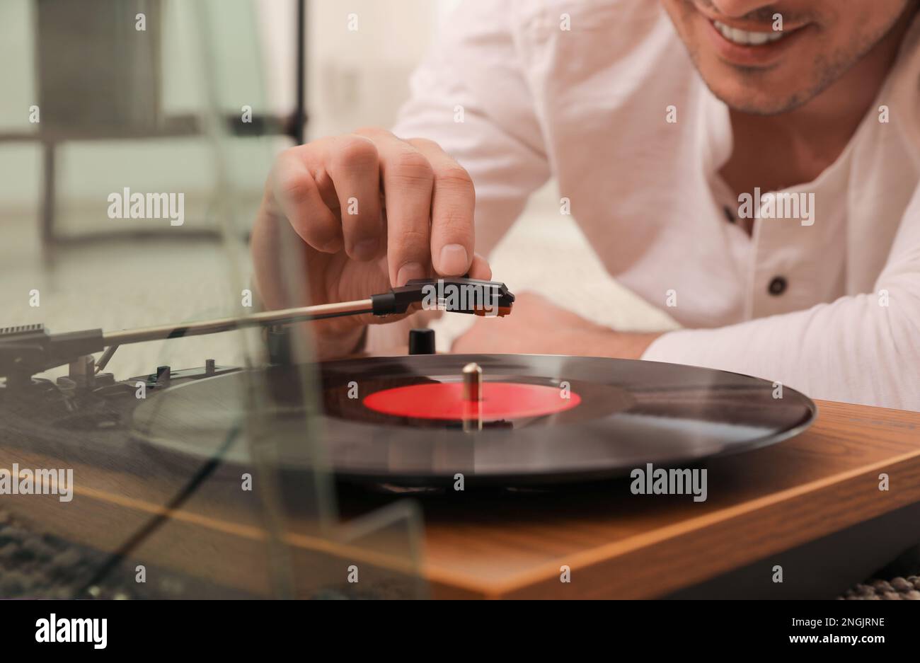 Uomo felice che usa il giradischi a casa, primo piano Foto Stock