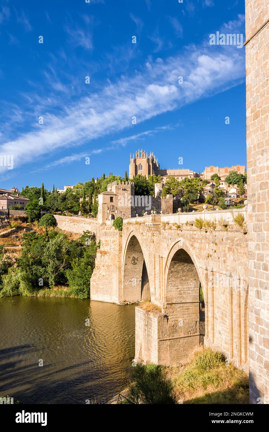 Vista del Ponte di San Martin che attraversa il Tago per entrare nella città vecchia di Toledo sulla collina dove si vede la Cattedrale Vecchia Foto Stock