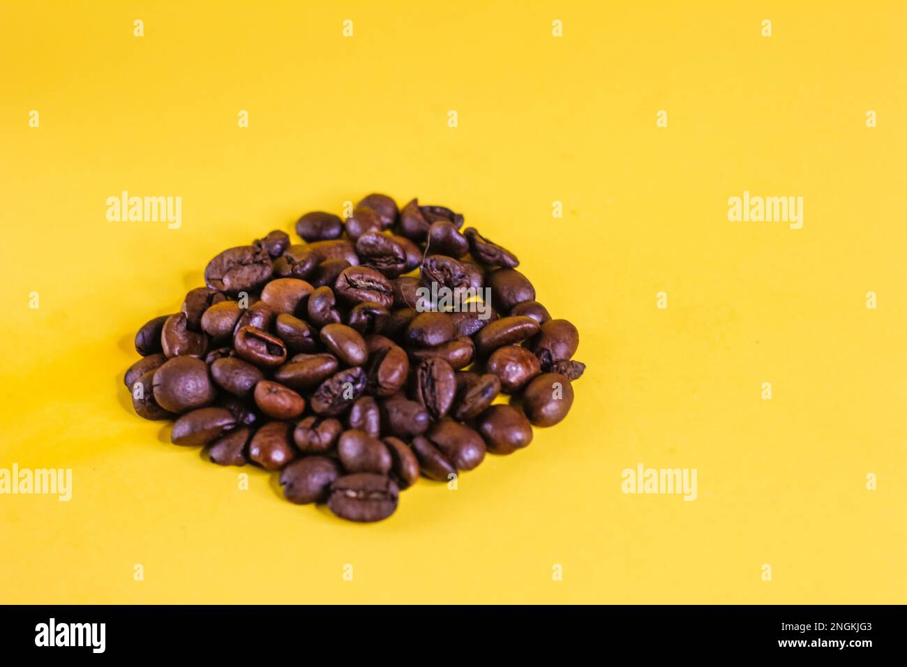 chicchi di caffè per preparare una bevanda, molti oggetti friabili, lance di colore marrone, sparsi su uno sfondo giallo. chicchi di caffè concept object Foto Stock