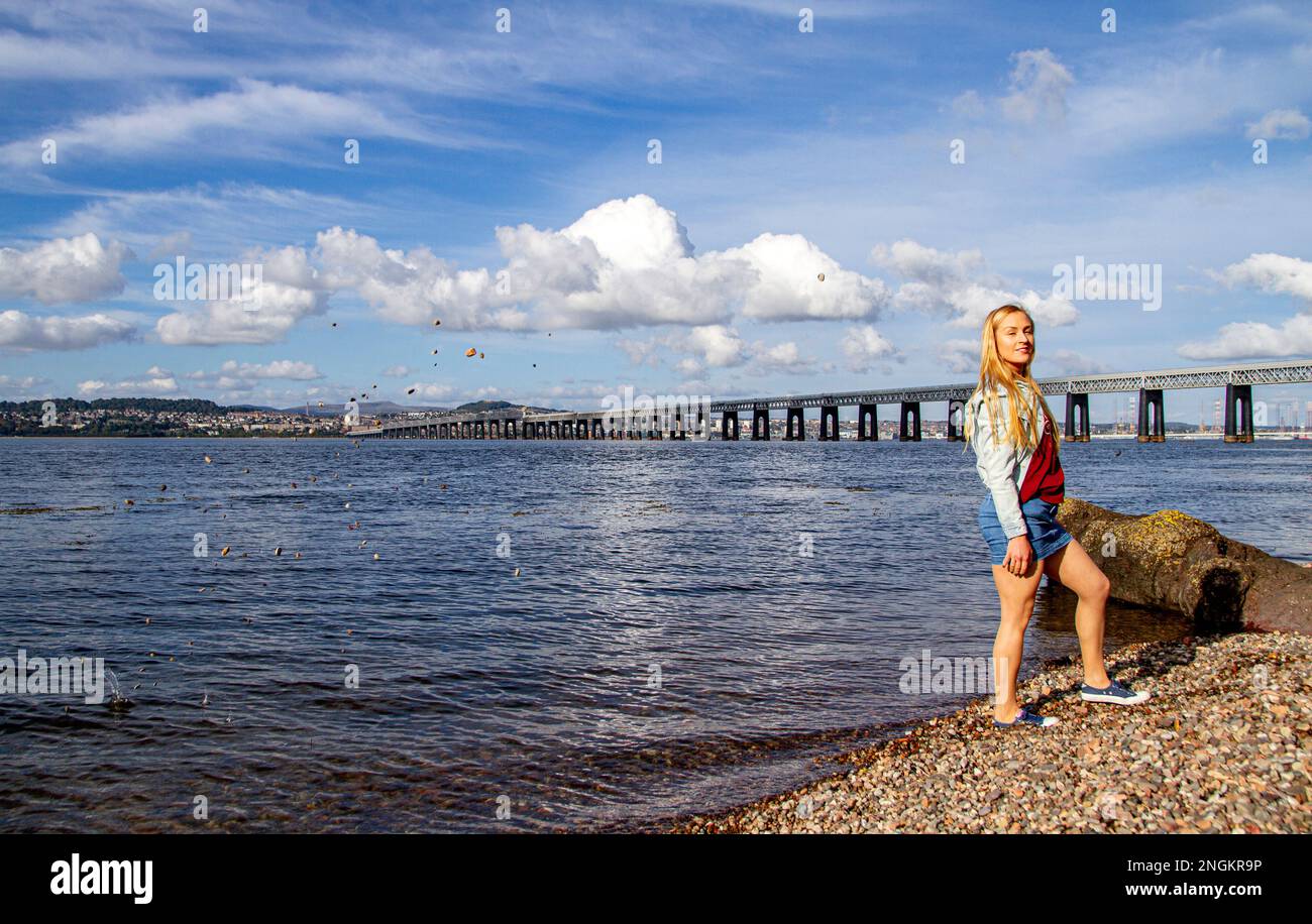 In una bella giornata di ottobre a Wormit Beach, Fife, Rhianna Martin getta ciottoli sulla sua testa nel fiume Tay, Scozia Foto Stock