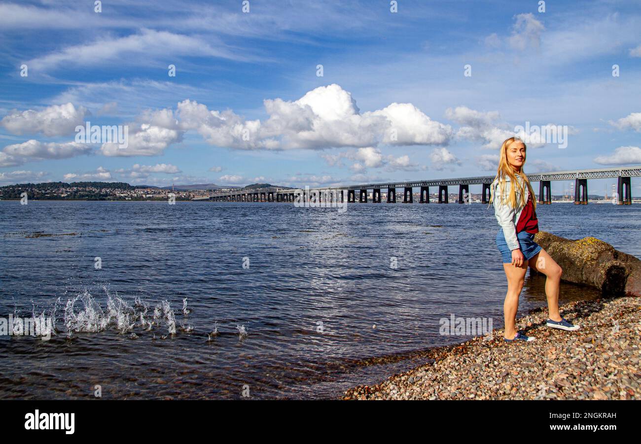 In una bella giornata di ottobre a Wormit Beach, Fife, Rhianna Martin getta ciottoli sulla sua testa nel fiume Tay, Scozia Foto Stock